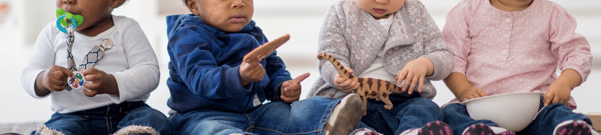 babies sitting together playing with toys
