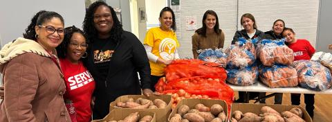 Volunteers behind tables of food for Thanksgiving food distribution