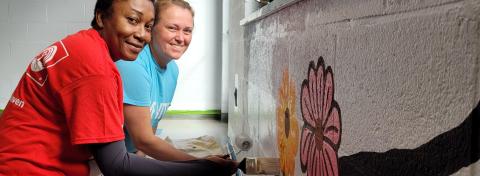 Volunteers painting and smiling